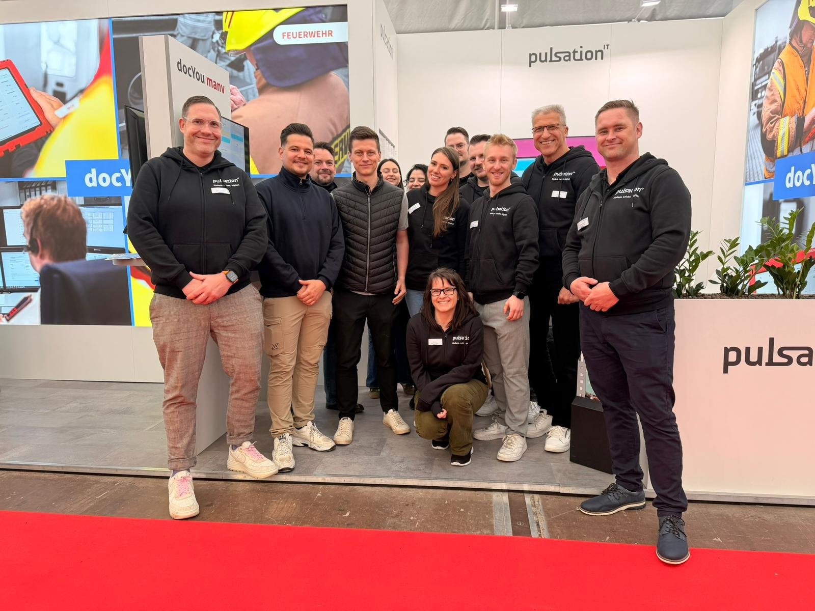 Mitarbeiter von pulsation IT stehen vor ihrem Messestand auf der RETTmobil 2026